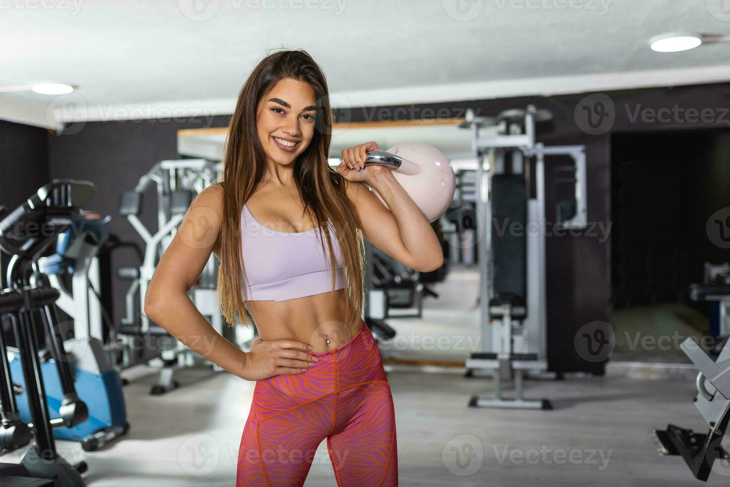 beeld van jong aantrekkelijk vrouw aan het doen waterkoker klok oefening Aan Sportschool achtergrond. geschiktheid vrouw werken uit. crossfit oefening. foto