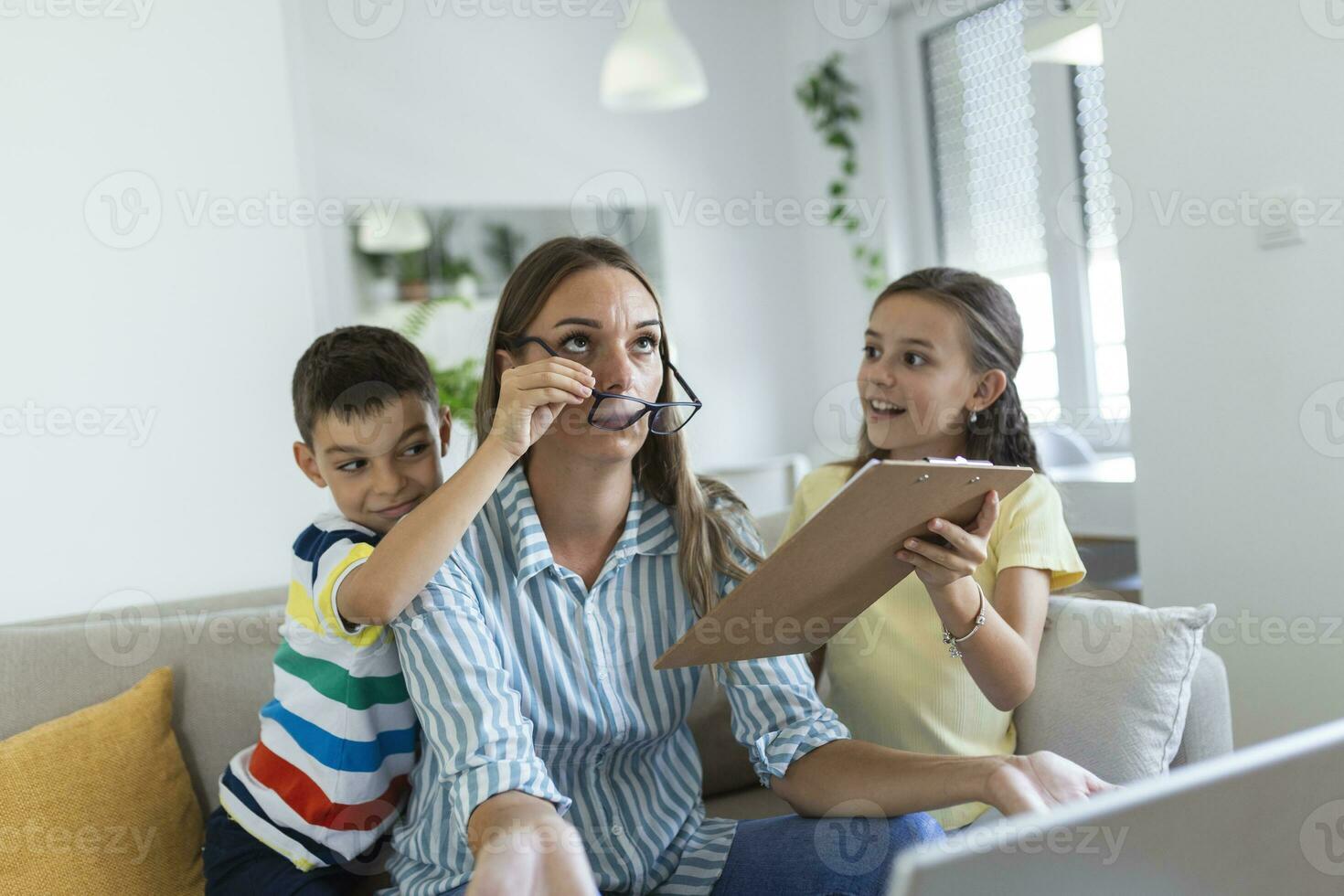 van streek moeder hebben probleem met luidruchtig ondeugend dochter en zoon jumping Aan bankstel en schreeuwen, veeleisend aandacht, gefrustreerd mamma moe van moeilijk kind proberen naar werk van huis foto