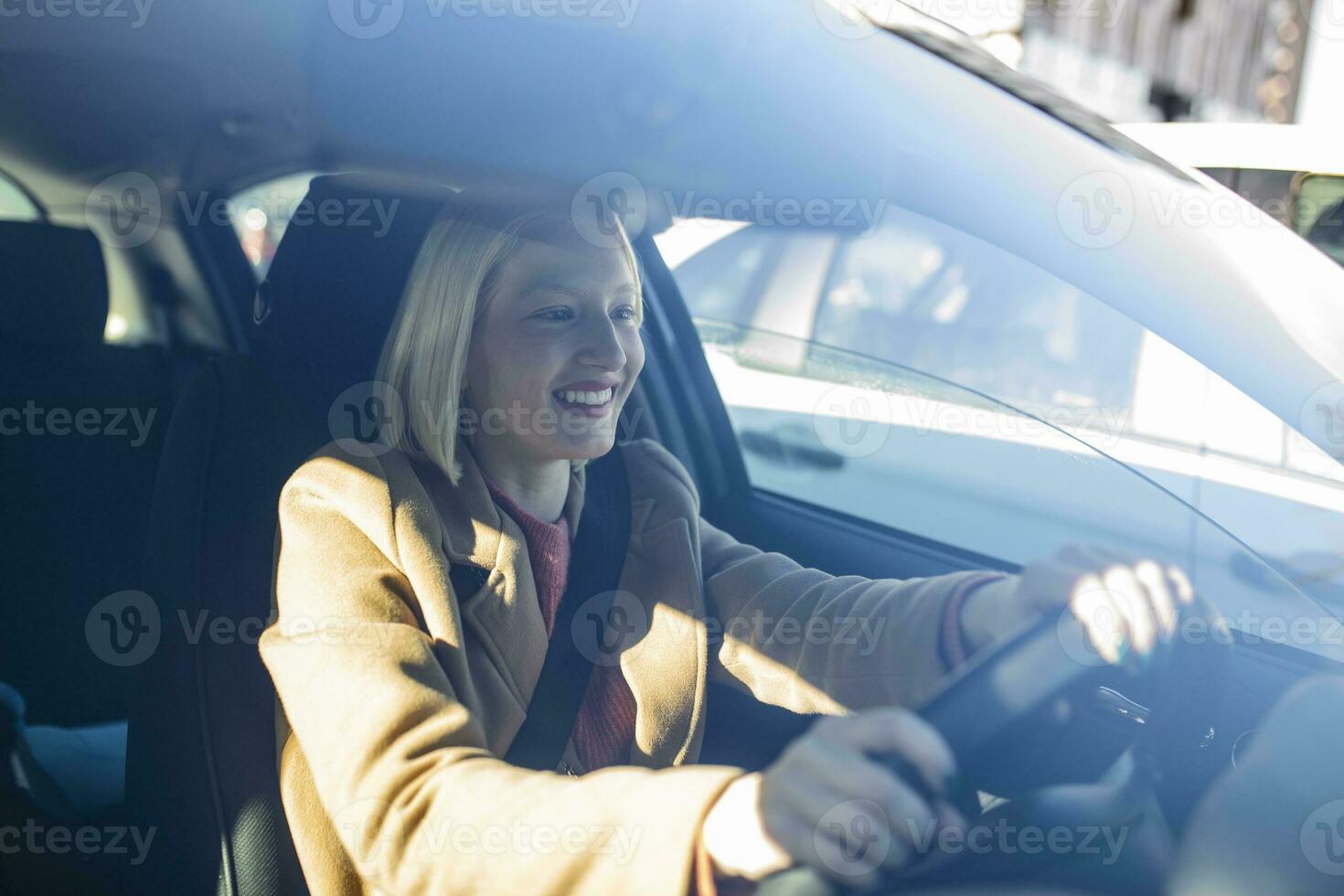 gelukkig blond vrouw het rijden een auto. portret van mooi Kaukasisch vrouw met toothy glimlach het rijden auto. hand- Aan stuurinrichting wiel. jong vrouw het rijden een auto in de stad foto