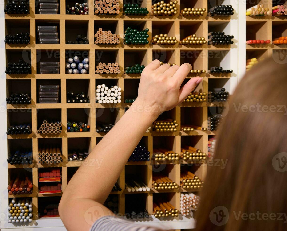 detailopname achterzijde visie van een vrouw klant kiezen grafiet potloden Aan een plank, in een kantoor levering op te slaan. kunst winkel. hobby foto