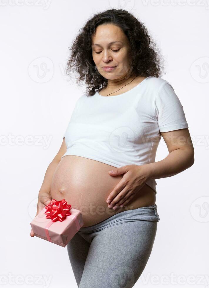 gelukkig moeder vrouwen dag. zwangerschap moederschap bevalling. gravid vrouw Holding geschenk doos over- wit geïsoleerd achtergrond foto