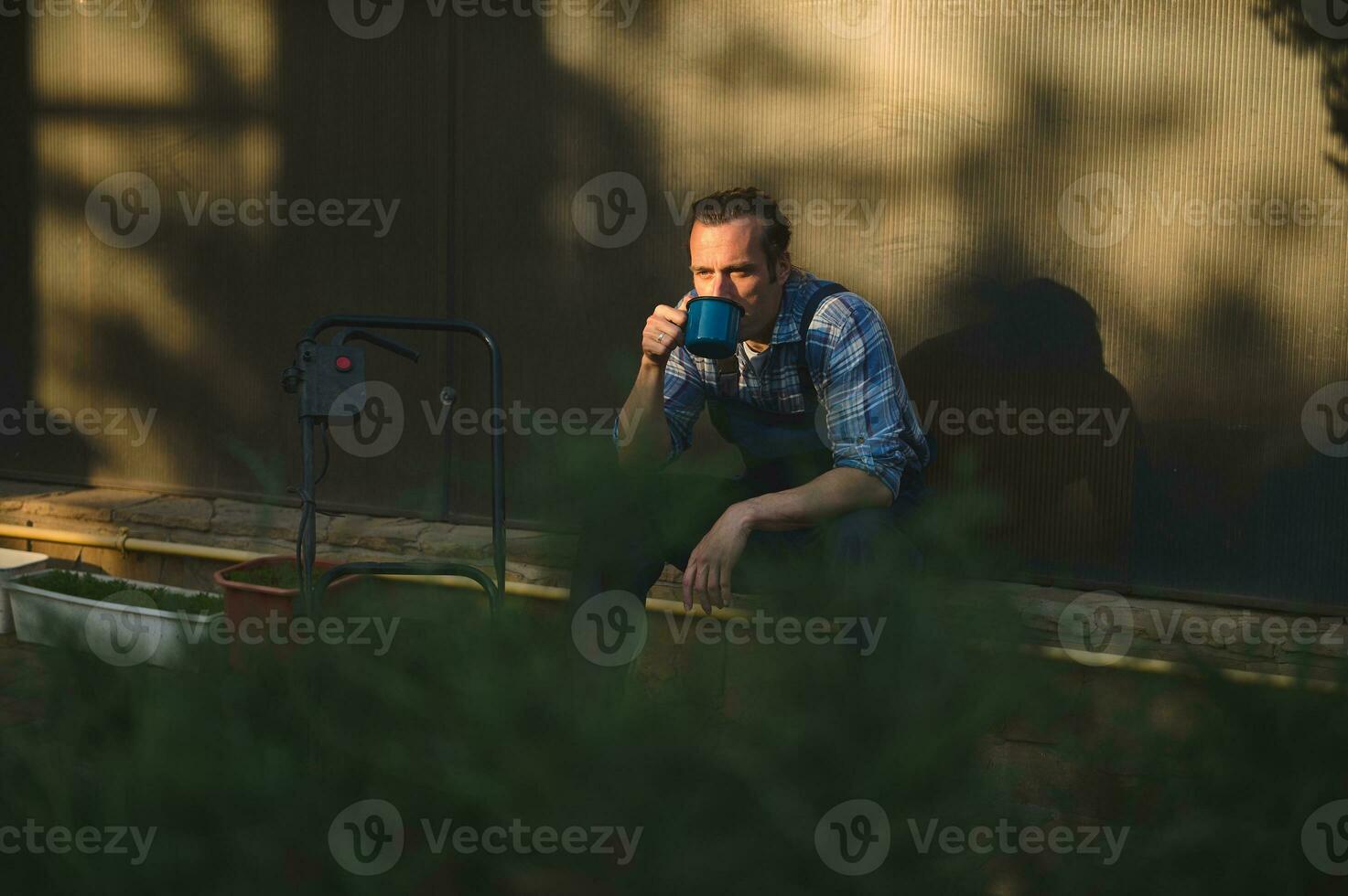 visie door haag Aan voorgrond naar professioneel tuinarchitect tuinman drinken koffie aking breken na moeilijk werken dag foto