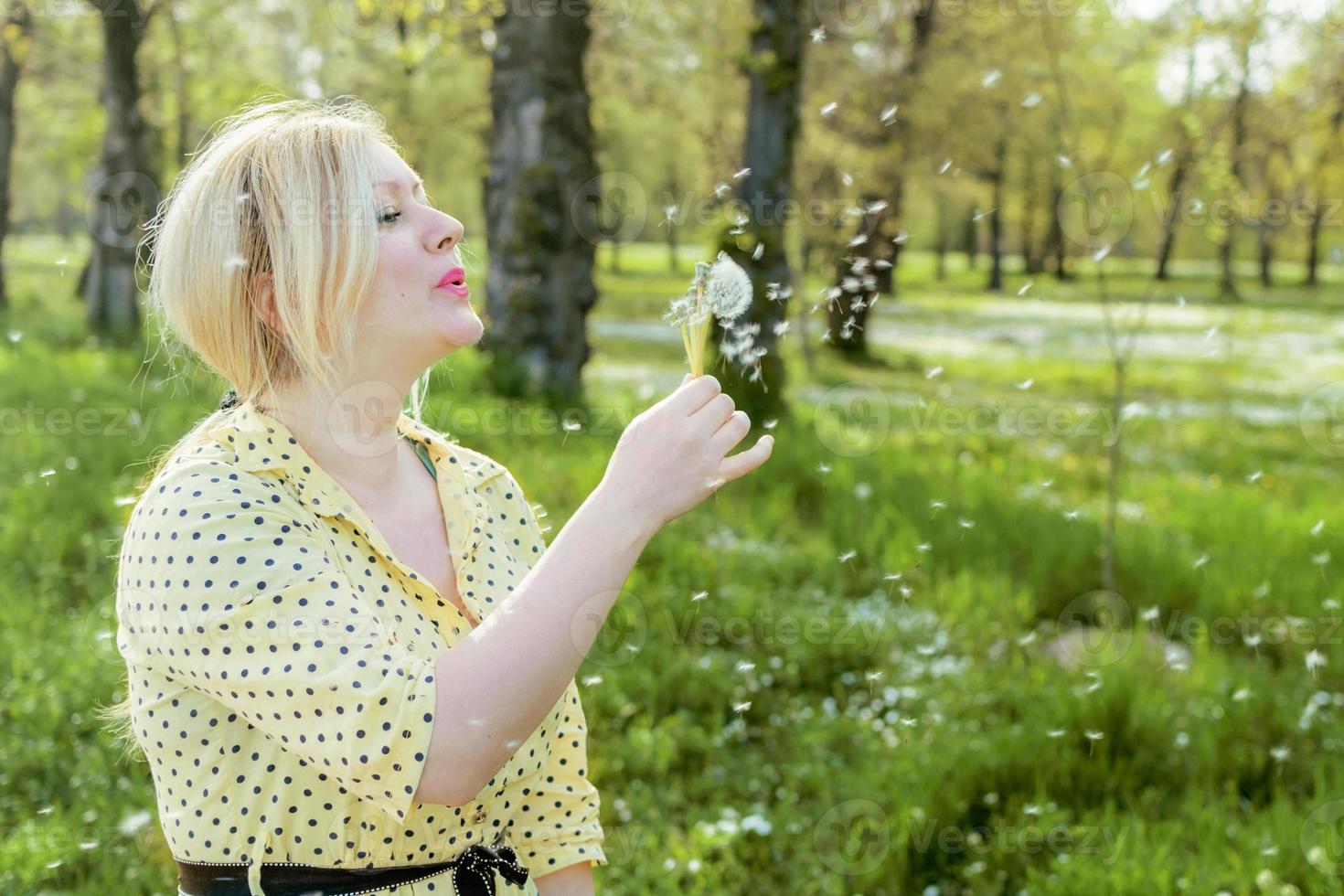 vrouw blaast een paardebloem foto