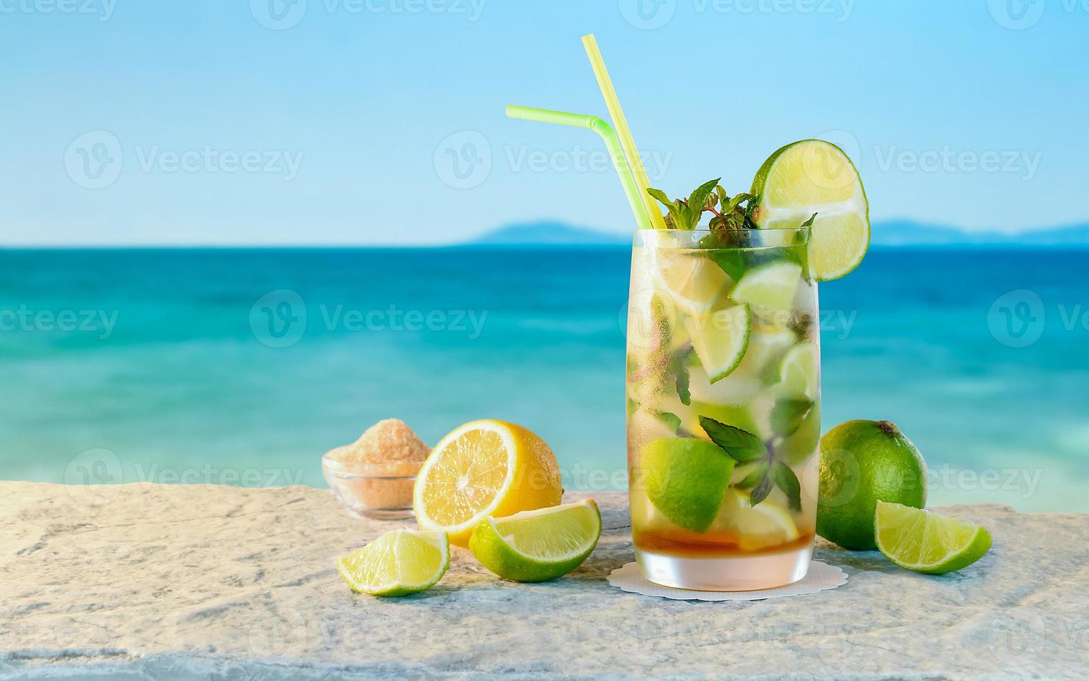 mojito-cocktail. witte rumcocktail met verse ingrediënten. koude ijsdrank op de achtergrond wazig strand. foto