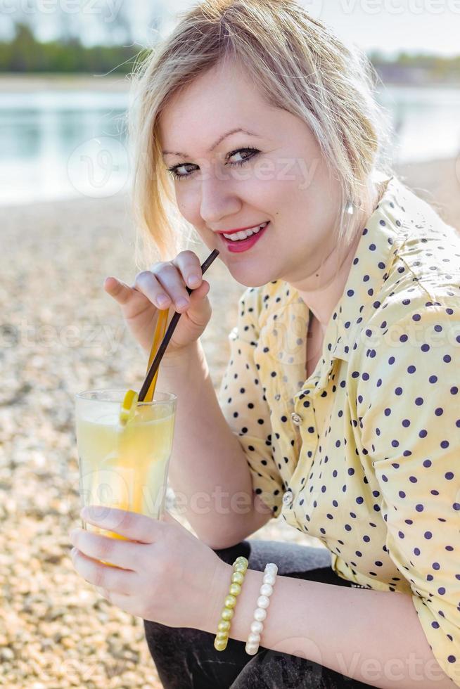 blond meisje geniet van haar limonade aan het meer foto