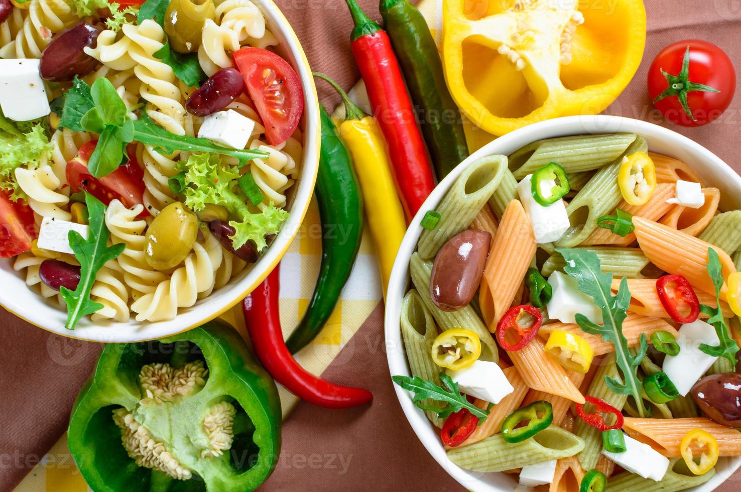 pastasalade met tomaat, rucola, komkommer, paprika, hete pepers, zwarte en groene olijven en kaas-feta. bovenaanzicht. foto