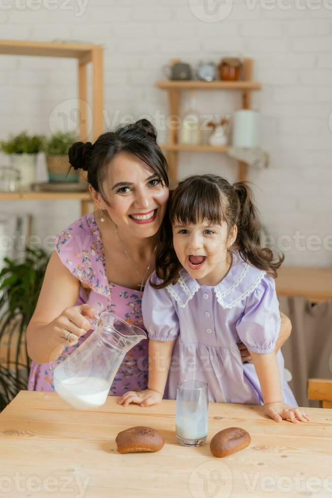 een weinig mooi meisje in een helder jurk is voor de gek houden in de omgeving van in de keuken foto