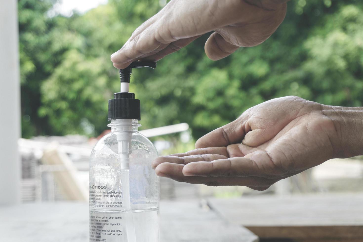 mannen handen met alcoholgel schoon wassen handdesinfecterend middel voor de gezondheidszorg anti corona virus coronavirus bacteriën vuile huidverzorging buitenshuis op groene natuur achtergrond foto