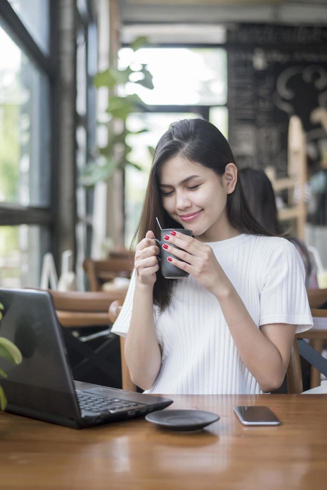 mooi zakelijk meisje dat werkt met tablet, smartphone en koffie drinkt in de coffeeshop foto