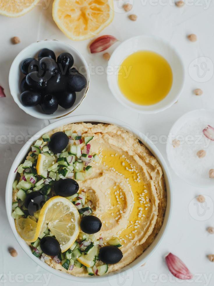 hummus van kikkererwten, met olijfolie, olijven, citroen, knoflook, sesamzaadjes, uien en komkommers. foto