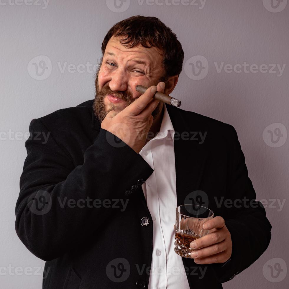 bebaarde man in moderne jas en shirt die zijn sigaar rookt foto