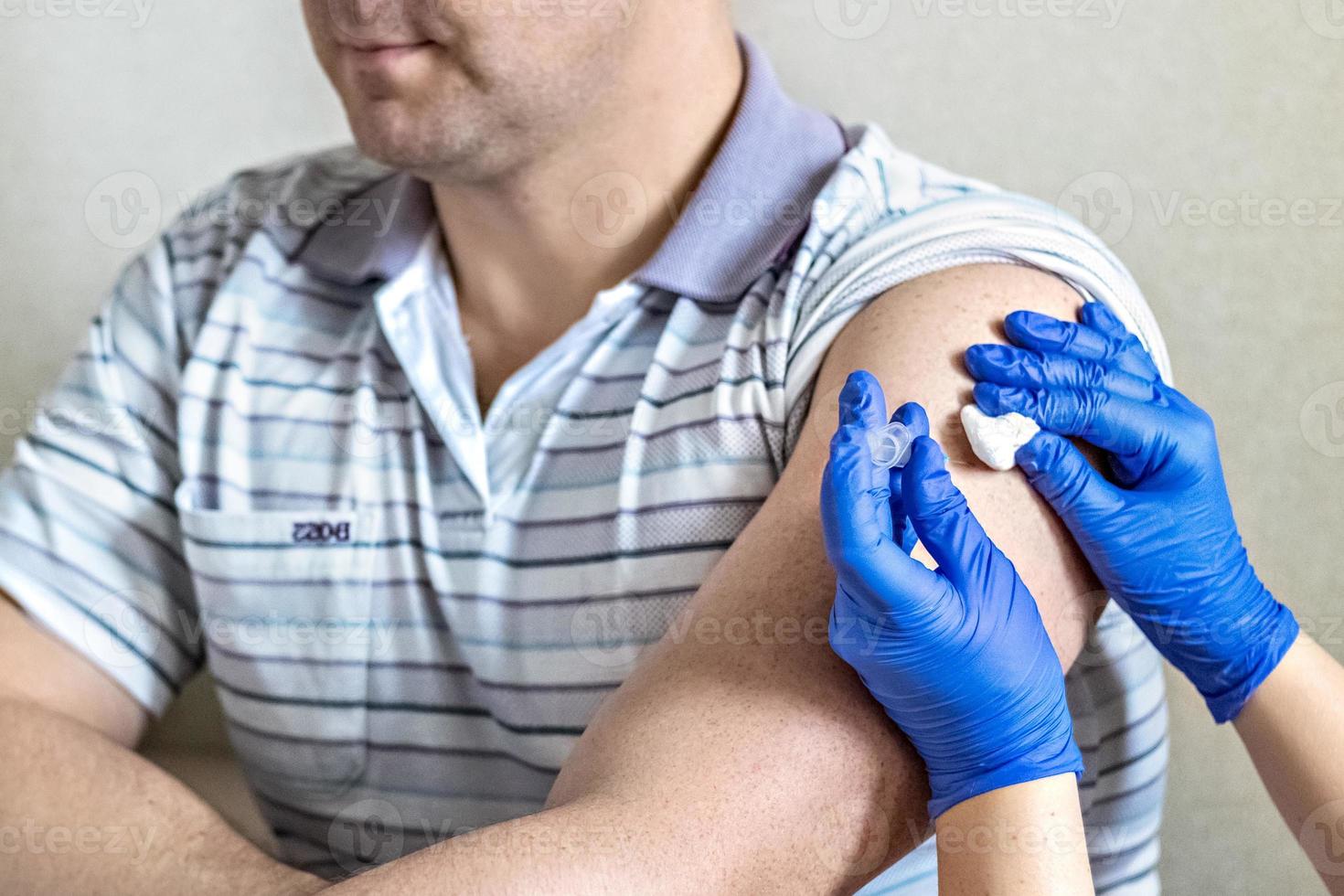 een arts vaccineert een man tegen het coronavirus in een kliniek. detailopname. het concept van vaccinatie, immunisatie, preventie tegen covid-19. foto