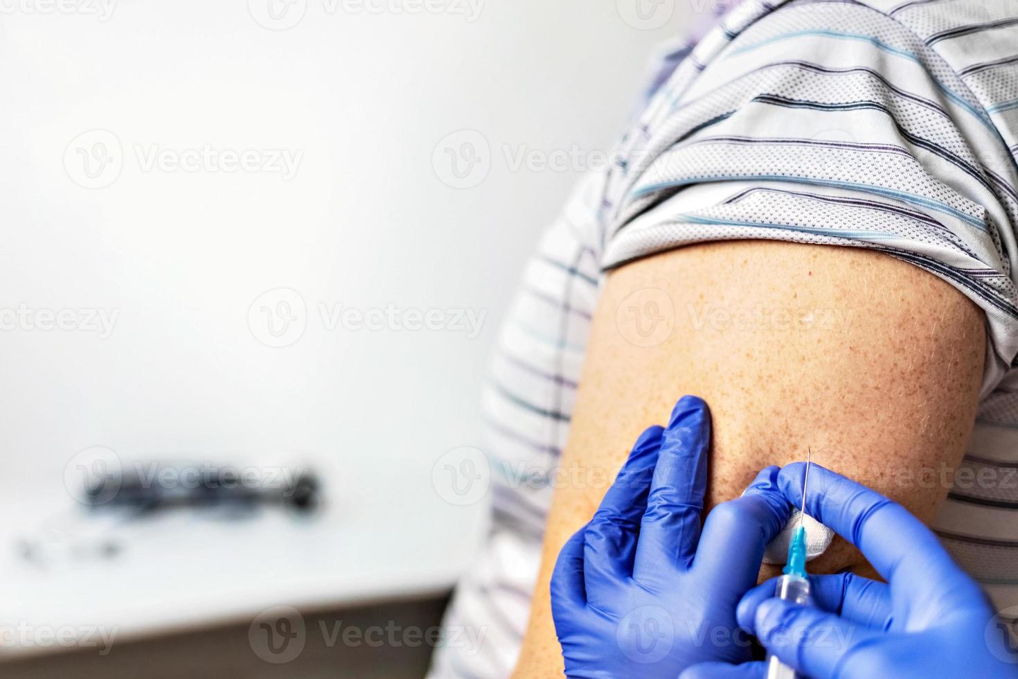 een arts vaccineert een man tegen het coronavirus in een kliniek. detailopname. het concept van vaccinatie, immunisatie, preventie tegen covid-19. foto