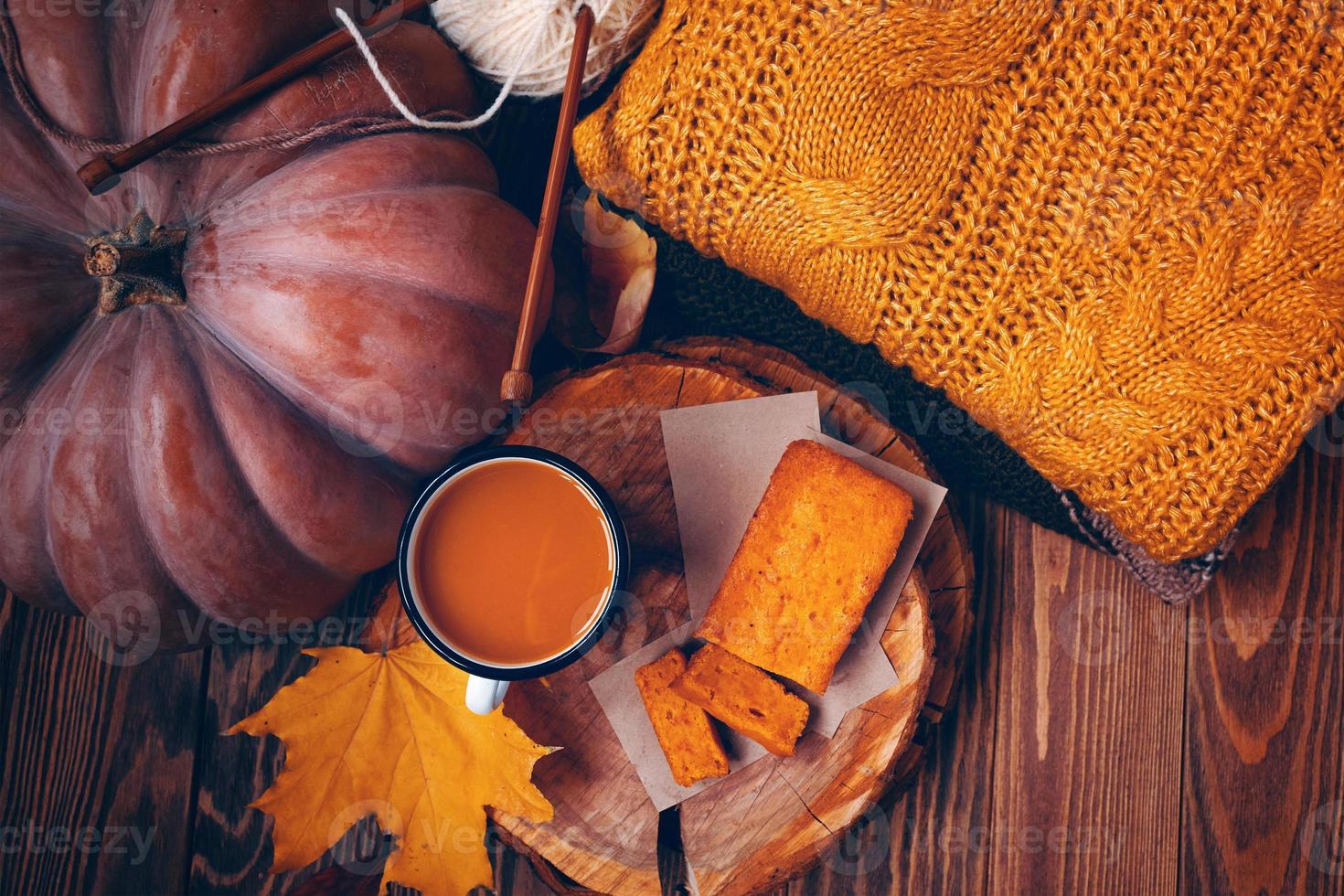 bovenaanzicht van de herfstcompositie met een kopje, een pompoen, een taart en een trui. foto