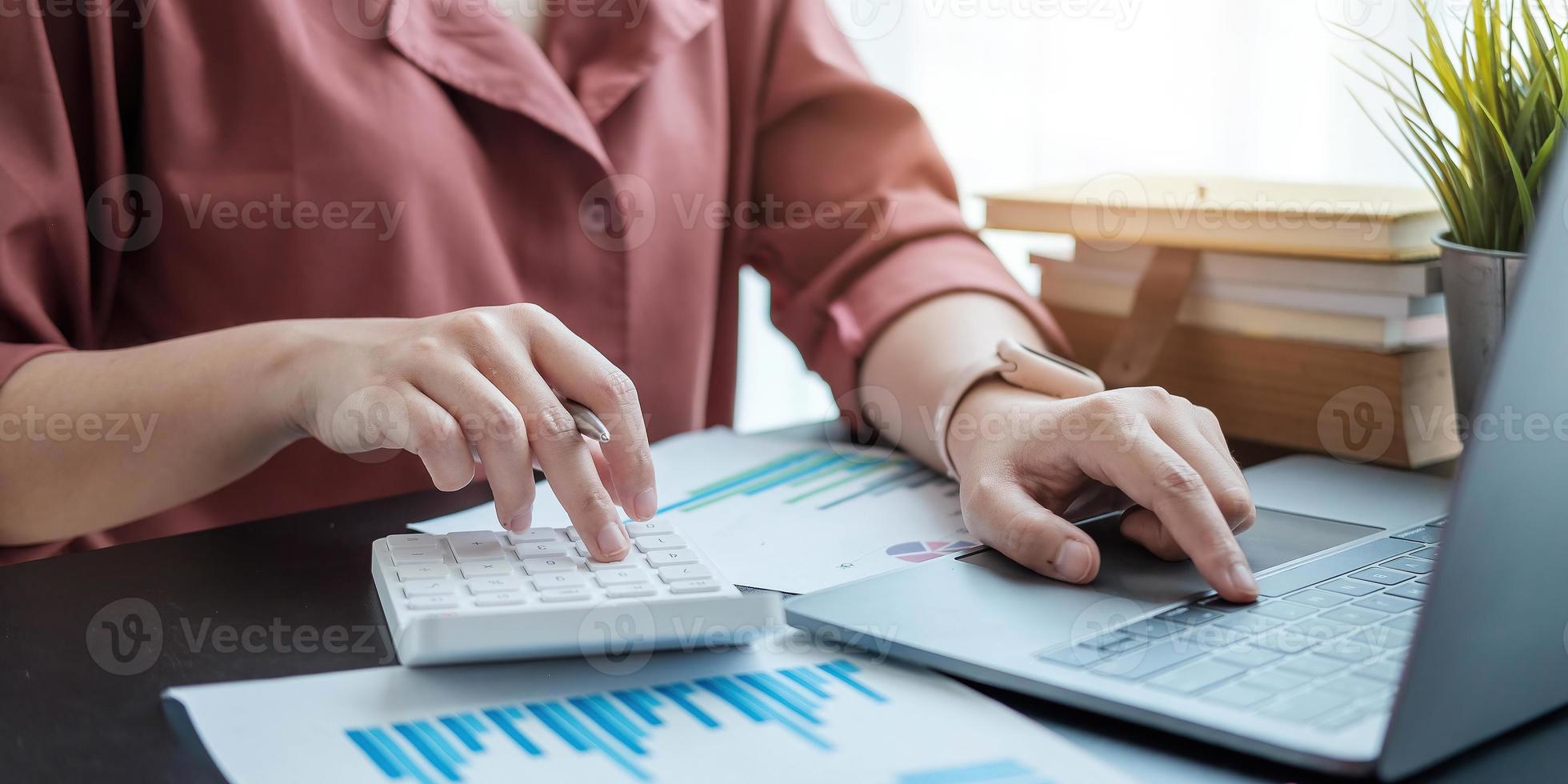 vrouw met financieel verslag en rekenmachine. vrouw die rekenmachine gebruikt om het rapport aan de tafel op kantoor te berekenen foto