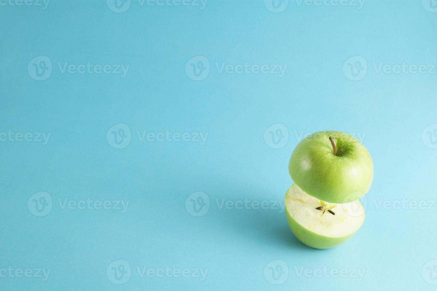 verse groene appel met een half vliegen op blauwe achtergrond. vliegende groene appel met lege kopie ruimte voor tekst. foto