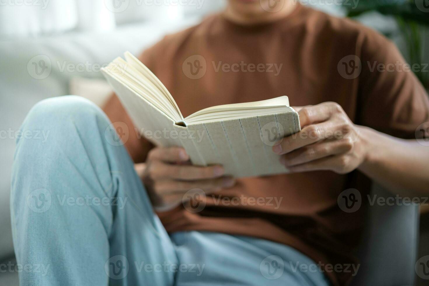 mannen lezing boek en ontspannende Bij huis en comfort in voorkant van geopend boek foto