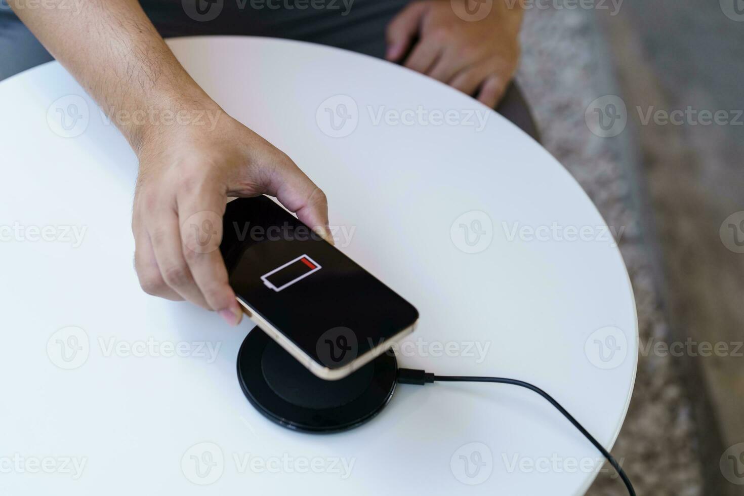 opladen mobiel telefoon accu met draadloze opladen apparaat in de tafel. smartphone opladen Aan een opladen kussen. mobiel telefoon in de buurt draadloze oplader modern levensstijl technologie concept. foto