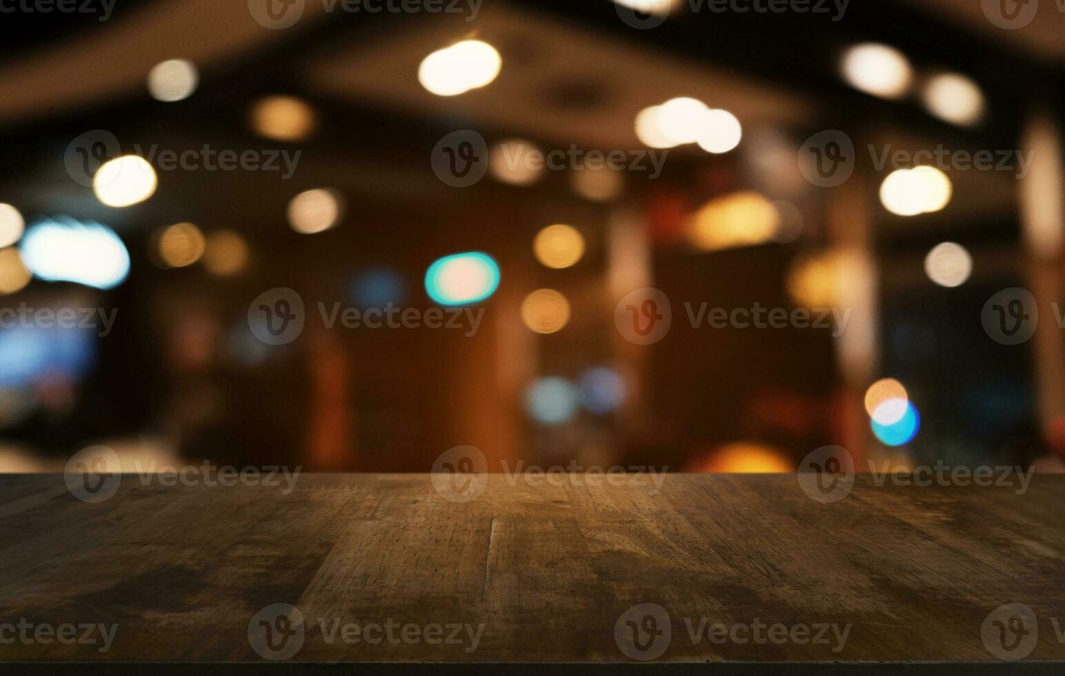 leeg donker houten tafel in voorkant van abstract wazig bokeh achtergrond van restaurant . kan worden gebruikt voor Scherm of montage uw producten.mock omhoog voor ruimte. foto