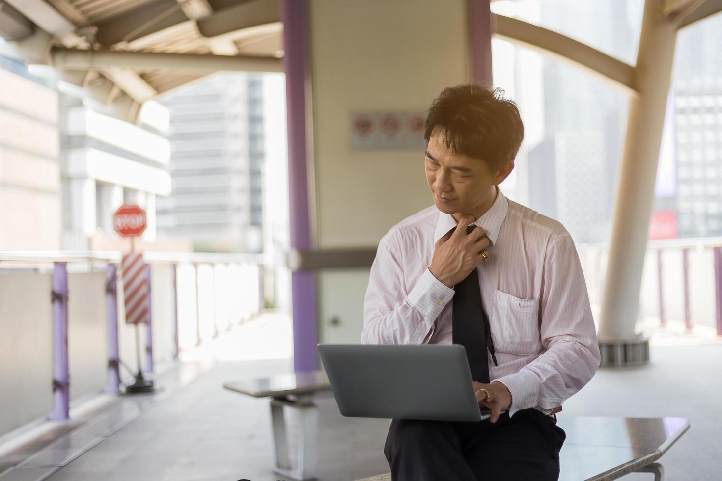 Aziatische zakenman die aan treinstation werkt foto