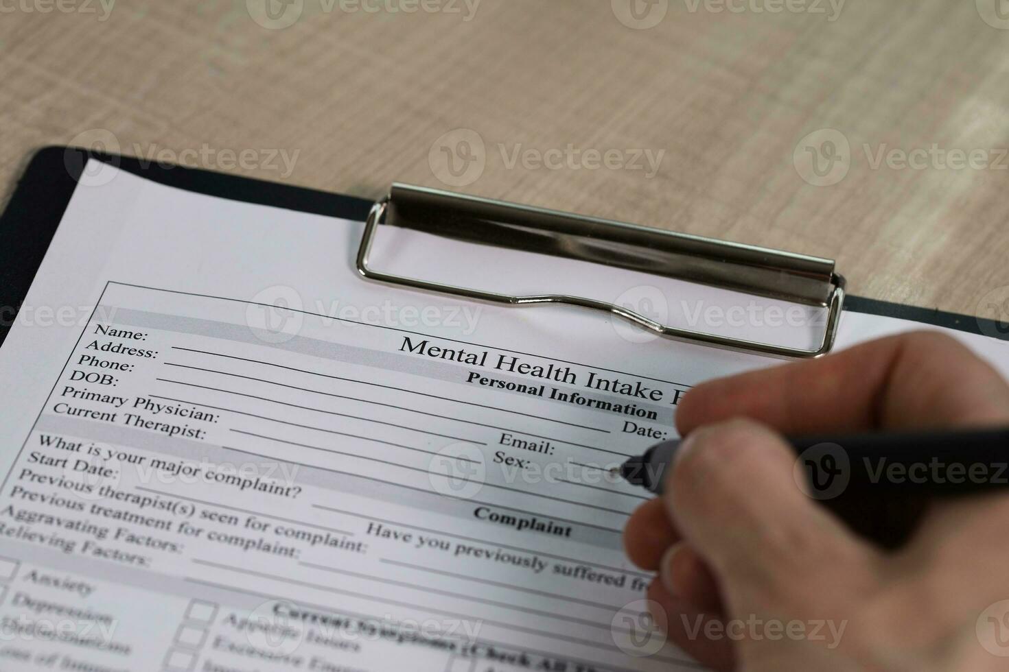 vrouw hand- is vulling omhoog de mentaal Gezondheid inname het formulier en een pen Aan een tafel. foto