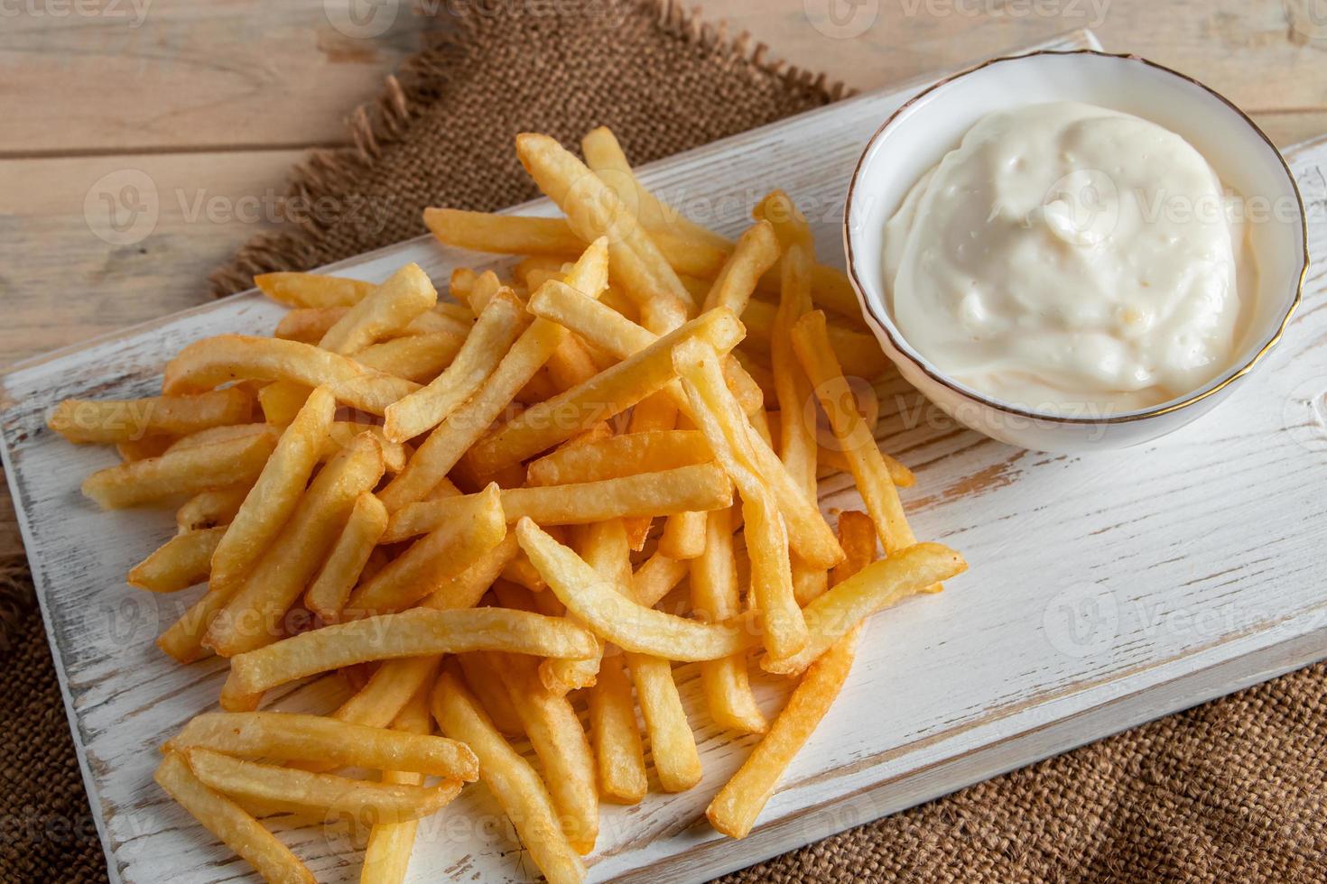 hete gouden frietjes met saus op houten achtergrond. zelfgemaakte rustieke gerechten. foto