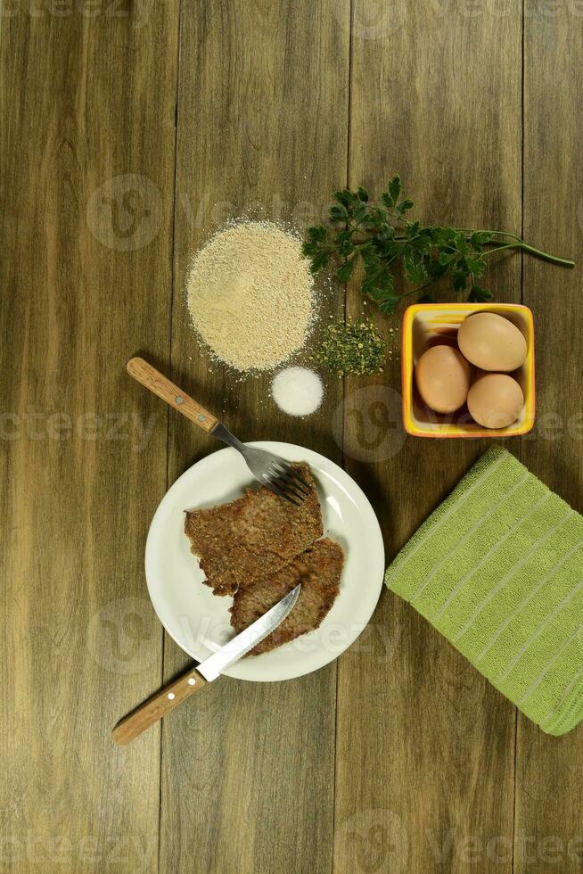 kalfsvlees milanees gepresenteerd Aan de tafel met ingrediënten foto