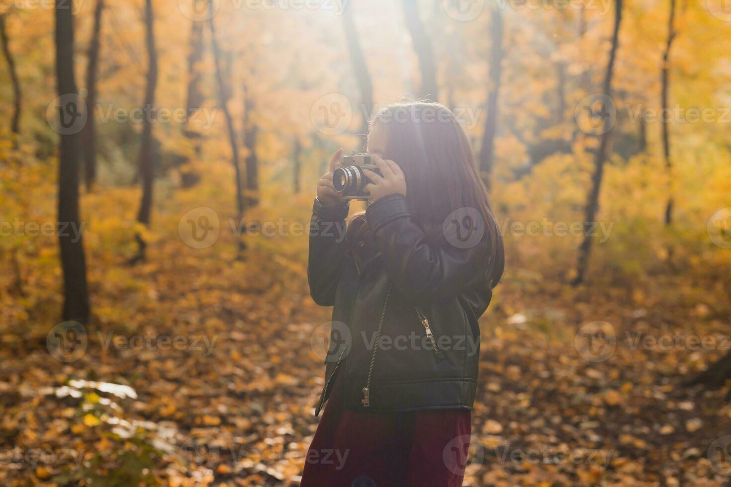 een weinig meisje nemen een foto met oud retro camera in herfst natuur. vrije tijd en hobby concept.