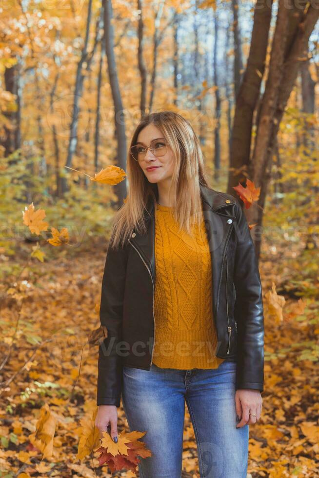 schattig smiley vrouw Holding herfst bladeren in vallen park. seizoensgebonden, levensstijl en vrije tijd concept. foto