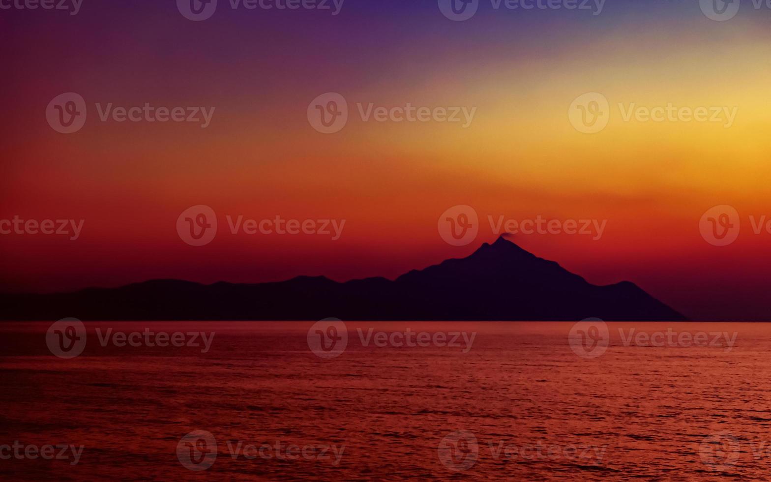 heilige berg athos bij zonsondergang. uitzicht vanaf het strand van platania, in de buurt van sarti, sithonia, schiereiland halkidiki, griekenland. foto