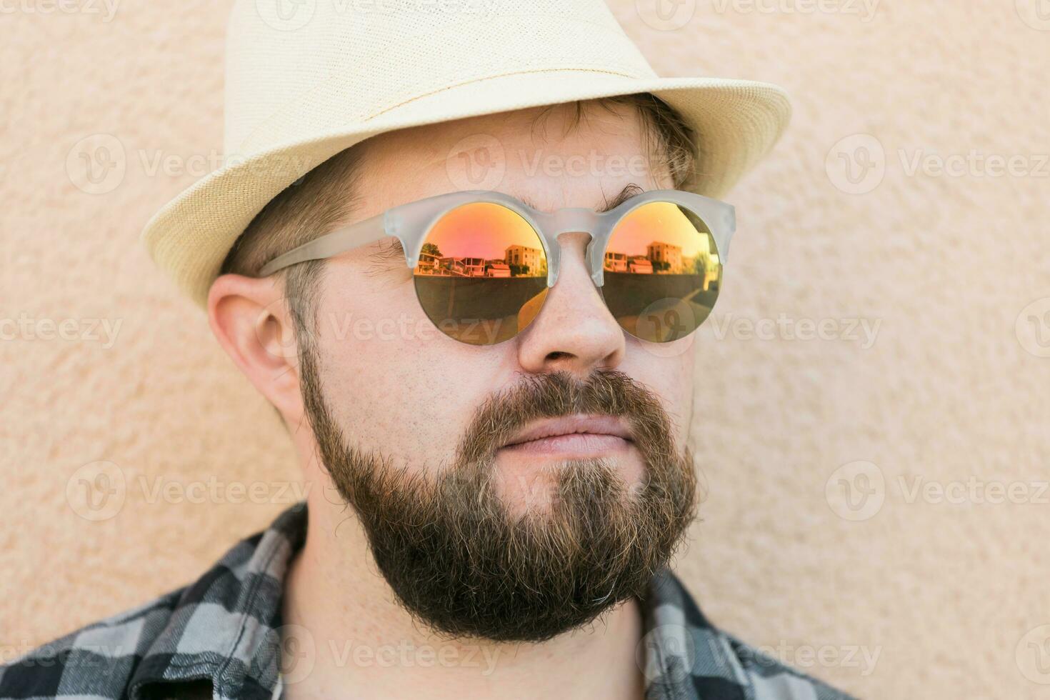 portret knap Mens vervelend zomer hoed en zonnebril en plaid overhemd glimlachen gelukkig in de buurt muur - reizen vakanties en zomer vakantie concept foto