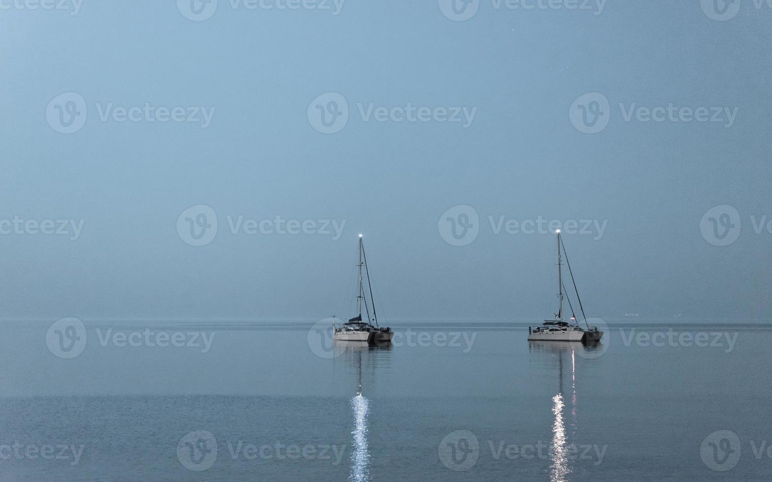 twee boten boven het maanlicht. twee verankerde schepen in de open zee onder het maanlicht, schiereiland kassandra, griekenland. foto