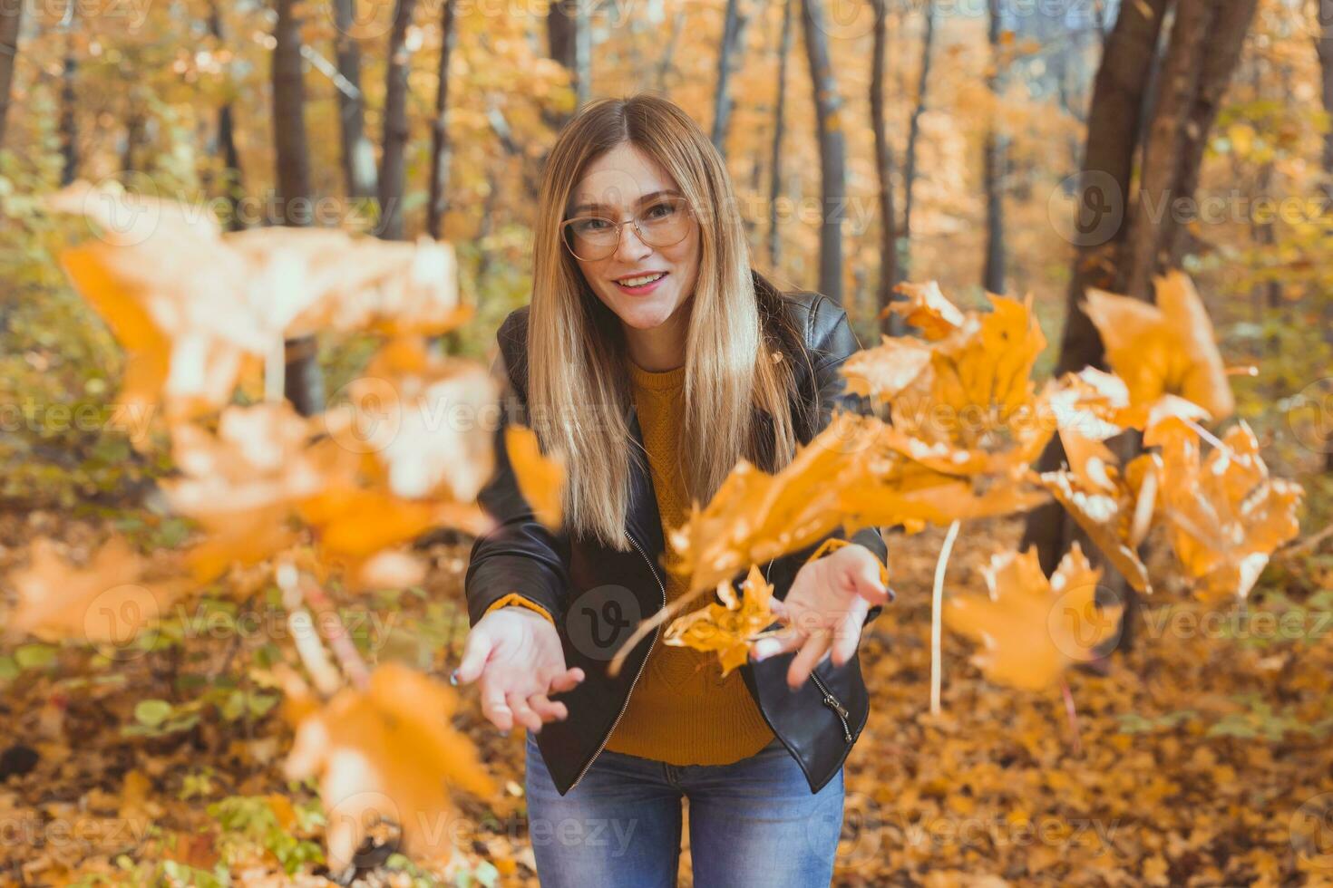 gelukkig lachend jong vrouw het werpen bladeren in herfst park. vallen seizoen foto