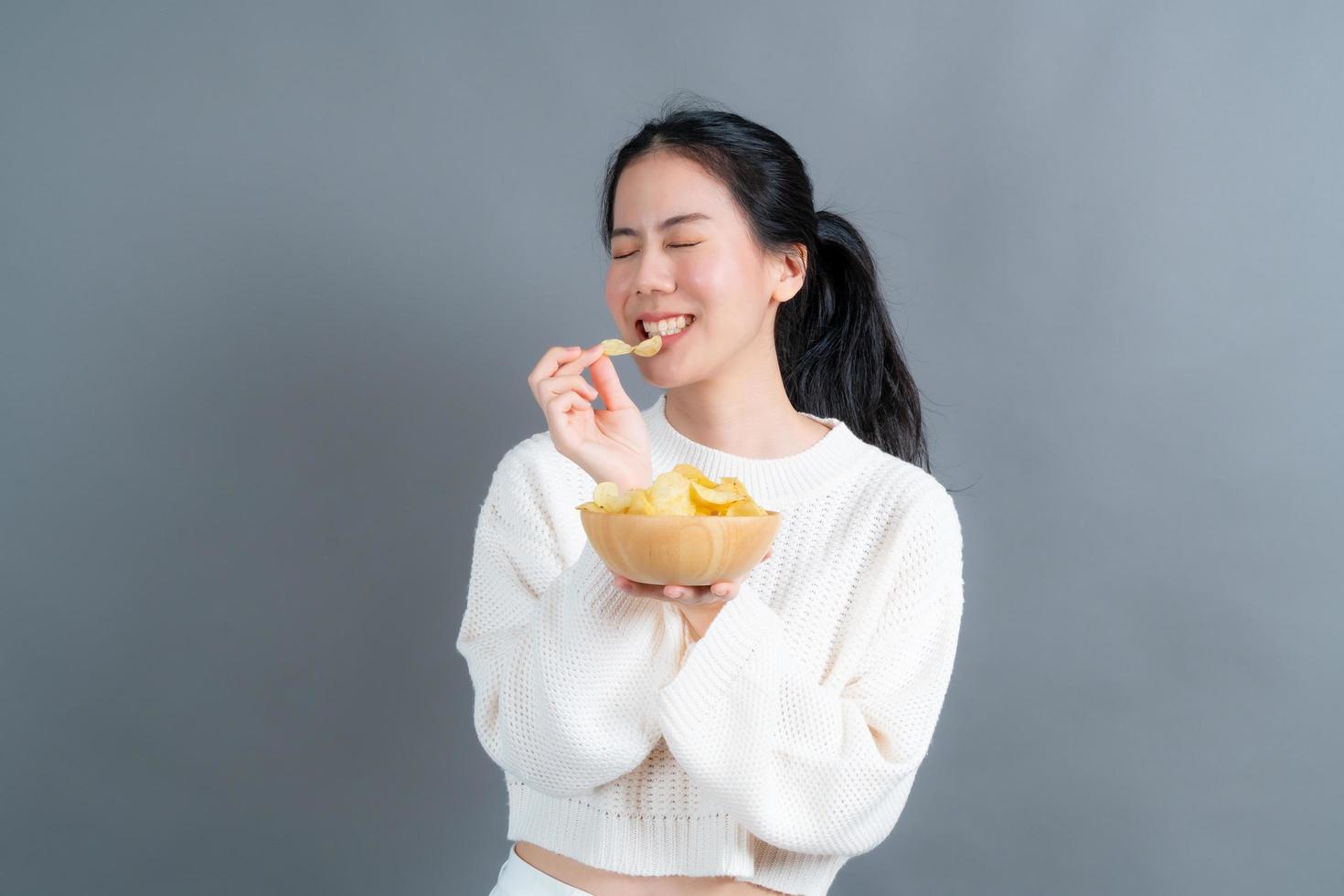 jonge aziatische vrouw eet chips foto