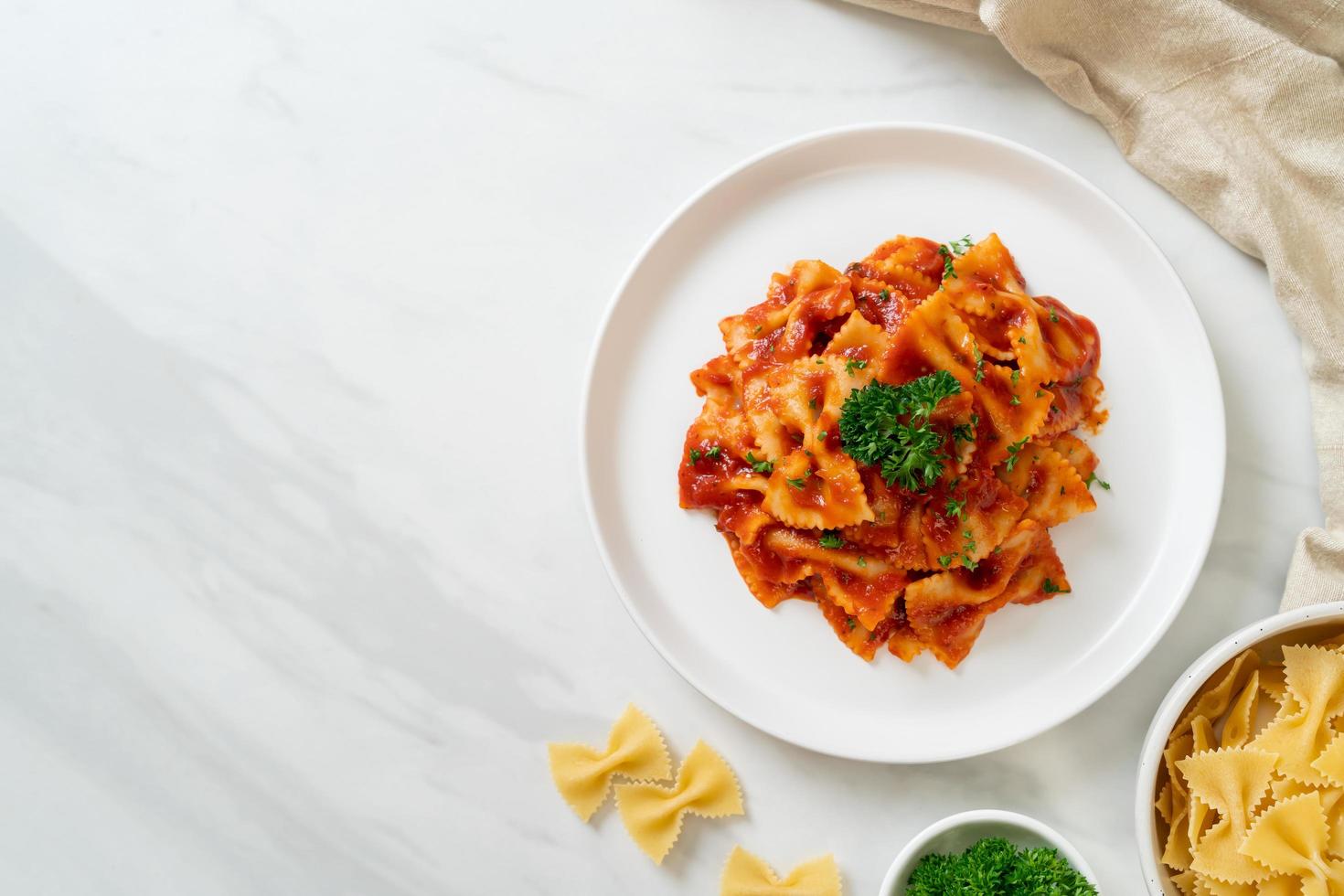 farfalle pasta in tomatensaus met peterselie - italiaans eten foto