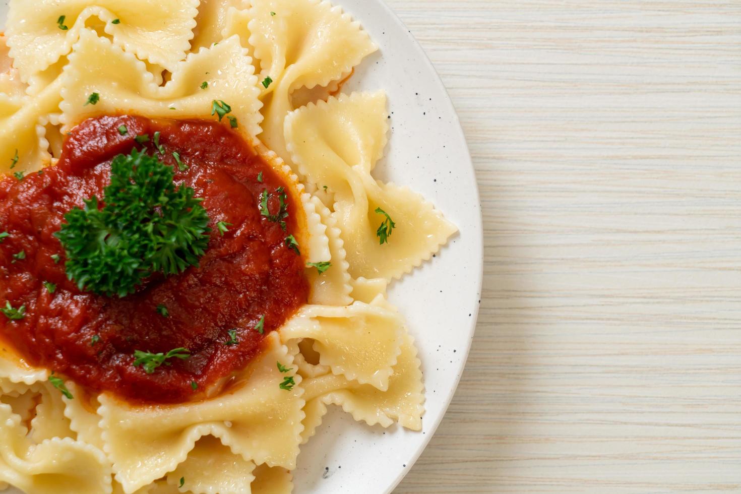 farfalle pasta in tomatensaus met peterselie - italiaans eten foto