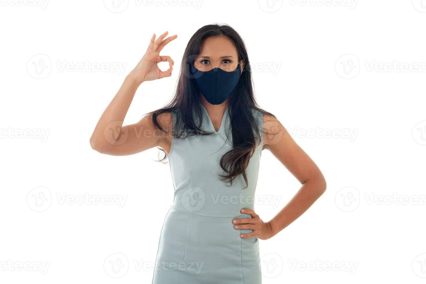 griep epidemie, stof allergie, bescherming tegen virus concept- studio portret van jong Aziatisch vrouw vervelend een gezicht masker en tonen OK teken met vingers, geïsoleerd Aan wit achtergrond foto