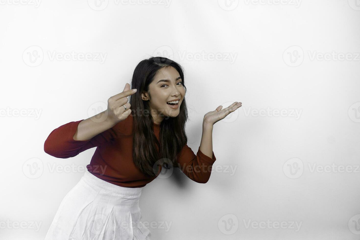 opgewonden Aziatisch vrouw vervelend rood t-shirt, richten Bij de kopiëren ruimte naast haar, geïsoleerd door wit achtergrond foto