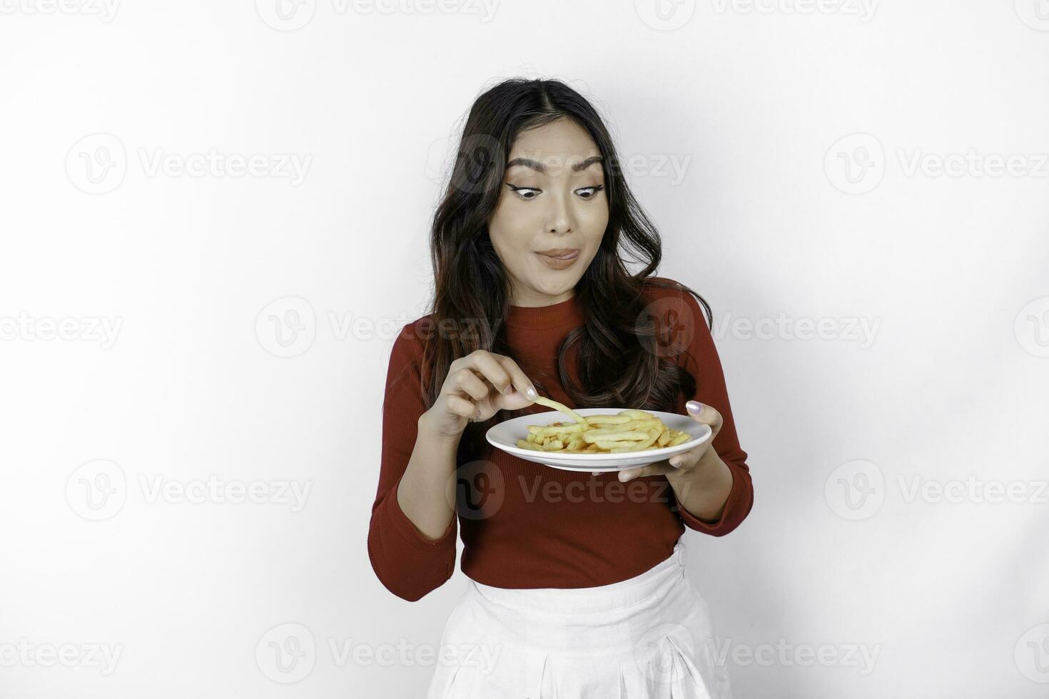 jong hongerig vrouw vervelend gewoontjes kleren houden een bord met snel voedsel Frans Patat aardappel geïsoleerd Aan wit achtergrond studio portret. mensen levensstijl voedsel concept foto