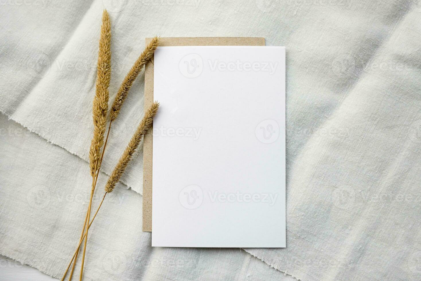 modieus voorraad schrijfbehoeften achtergrond - een wit kaart en takjes van tarwe oren Aan een wit tafel. romantisch achtergrond. blanco voor een uitnodiging kaart. foto