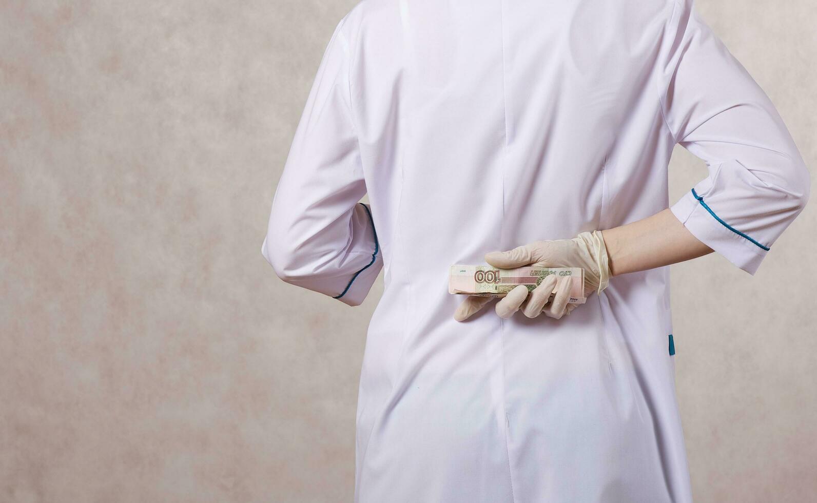 een jong vrouw gekleed in een medisch uniform verbergt een steekpenning foto