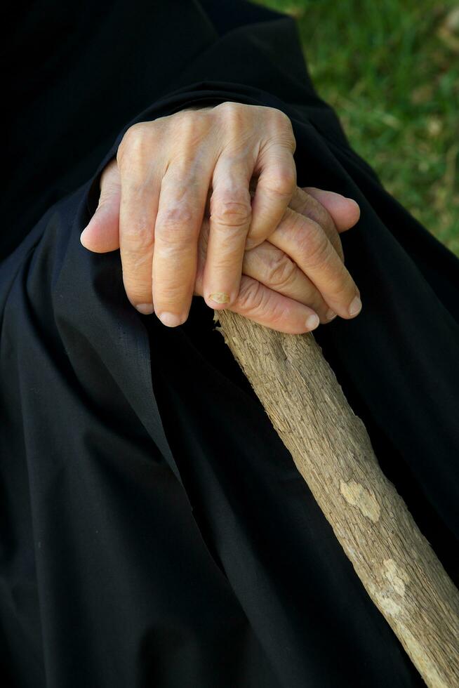 de handen van een oud vrouw Aan een houten stok foto