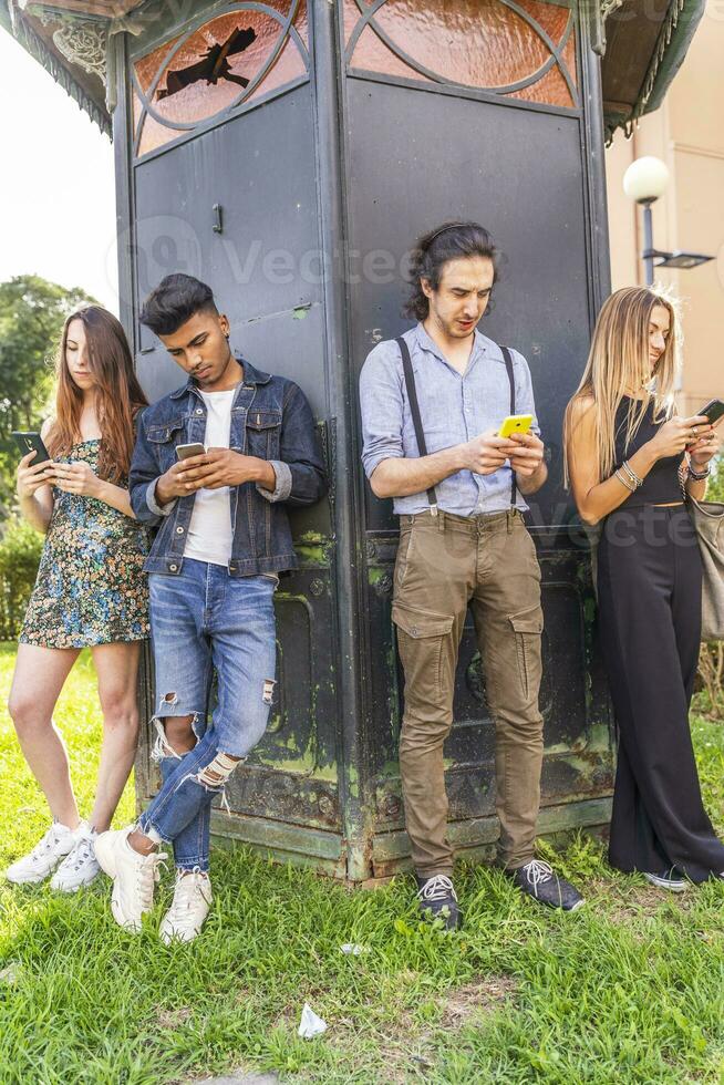 groep van multiraciaal vrienden in voorkant van een kiosk gebruik makend van smartphones foto