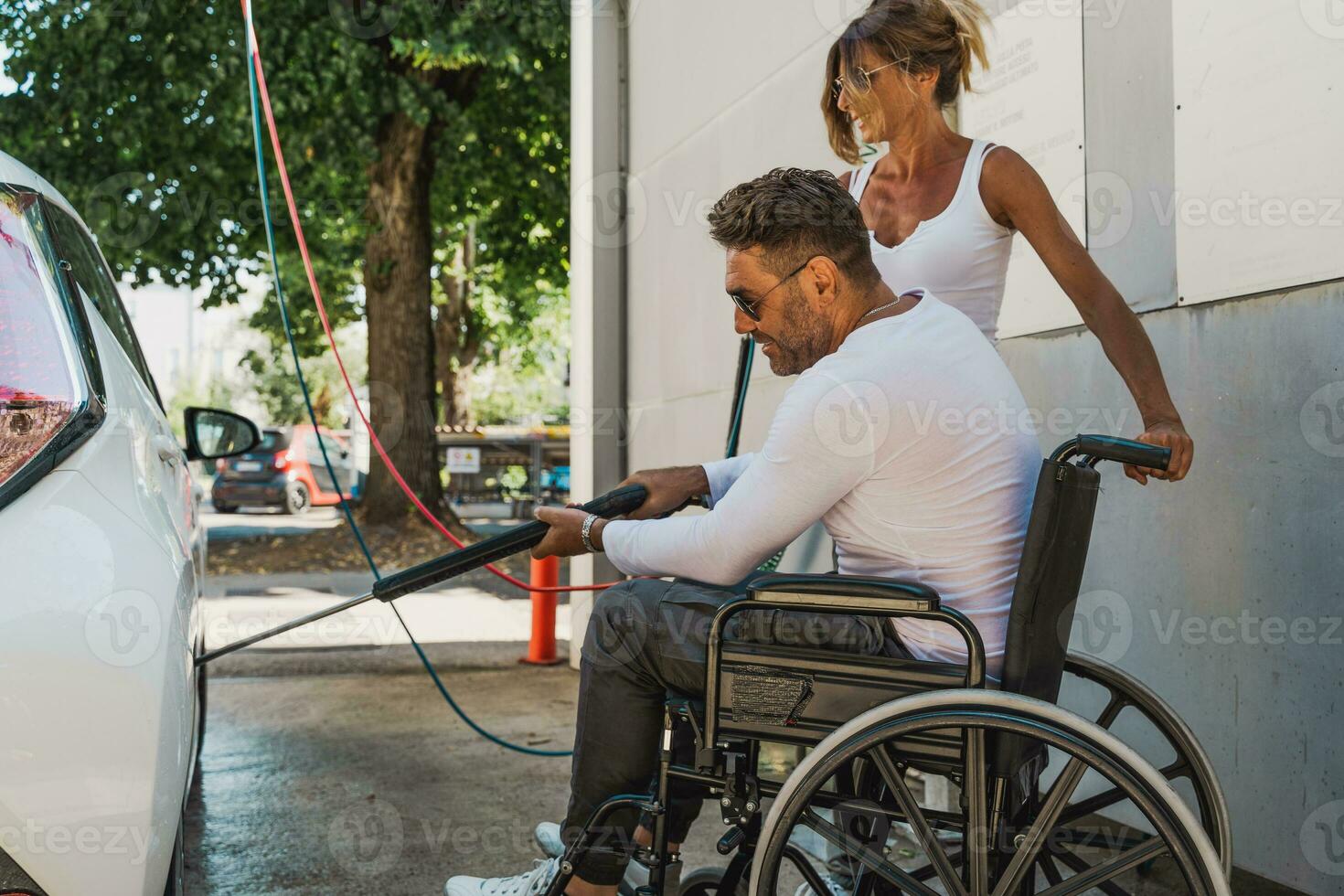 gelukkig midden- oud paar met Mens zittend Aan rolstoel het wassen auto Bij openbaar auto wassen foto