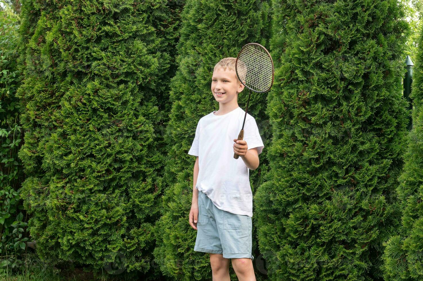 een gelukkig jongen houdt een badminton racket in zijn handen, buitenshuis activiteiten foto