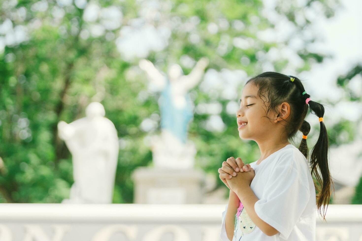 schattig Aziatisch kind meisje bidden in de park met kopiëren ruimte foto