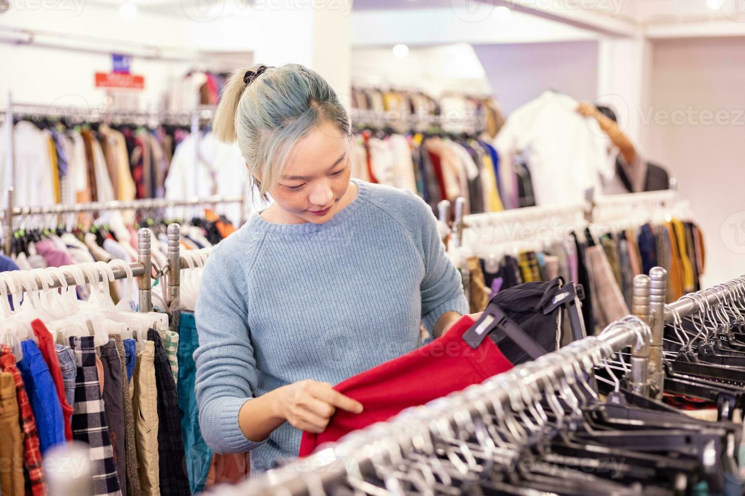 elegant Aziatisch vrouw is kiezen de tweede hand- trui van de kleding winkel voor winter seizoen mode naar houden warm Bij de nieuw jaar en Kerstmis vakantie foto