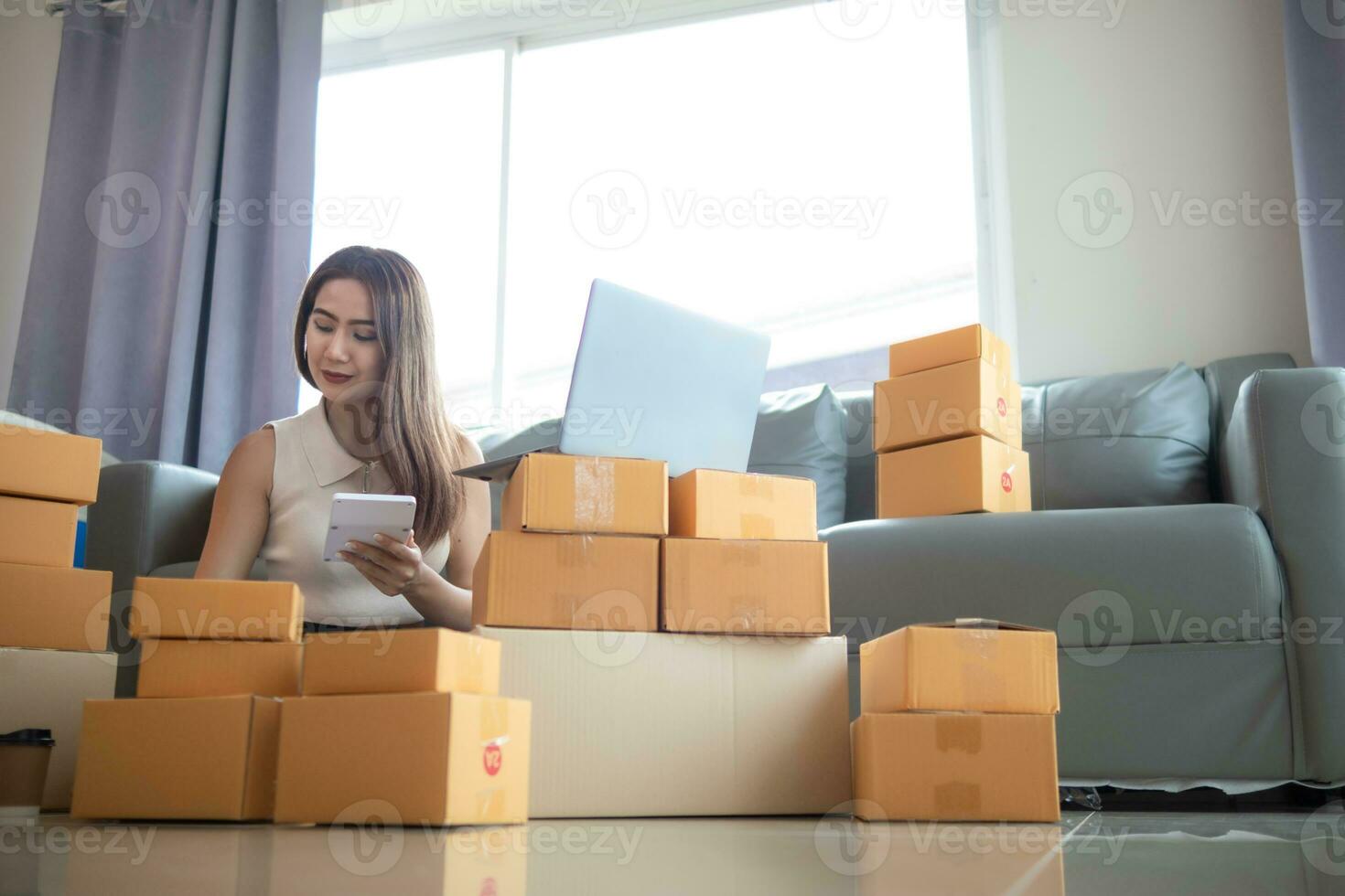 vrouw controle pakket van goederen van klant online bestellen is alleen in haar huis kantoor net zo ze is een mkb ondernemer en toepassingen haar telefoon en tablet naar markt online. concept online verkoop bedrijf foto