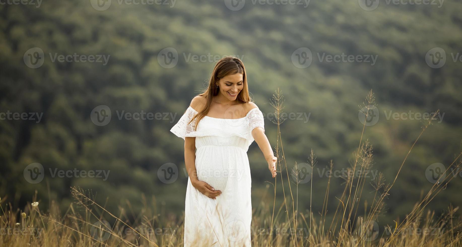 jonge zwangere vrouw op het veld foto
