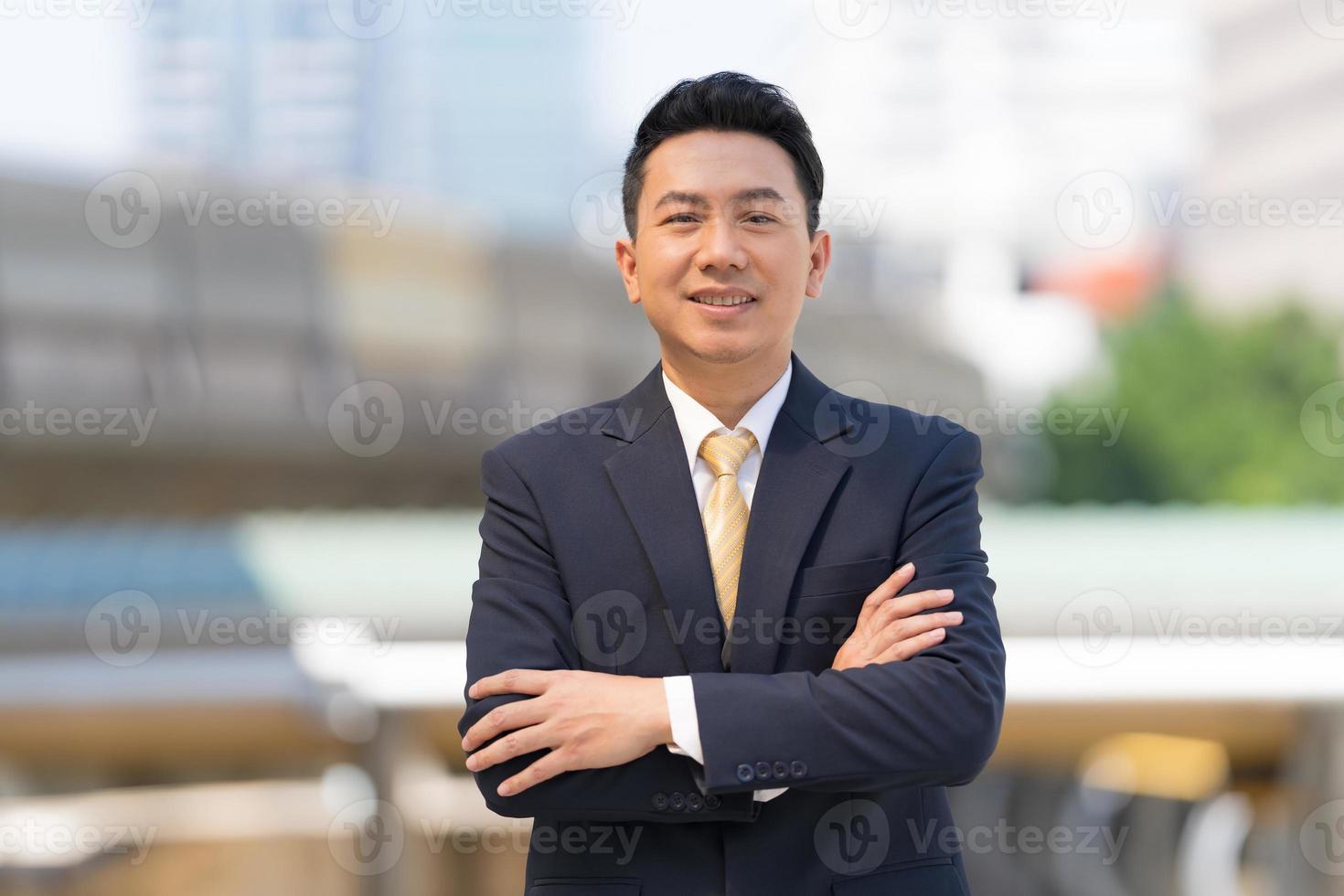 portret van een succesvolle zakenman die met gekruiste armen voor een modern kantoor staat foto